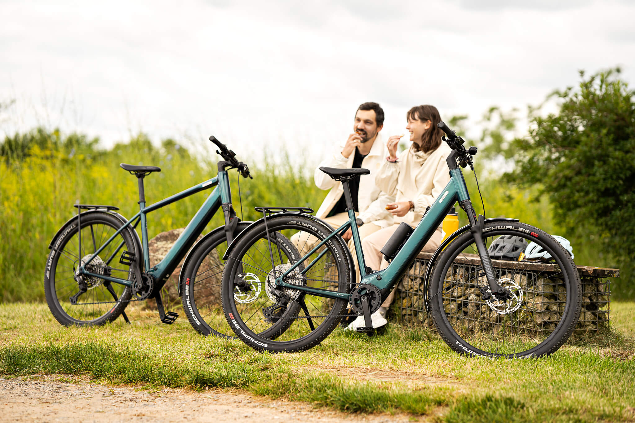 Mann und Frau sitzen neben leichten Coboc E-Bikes Skye Step und Skye auf Bank