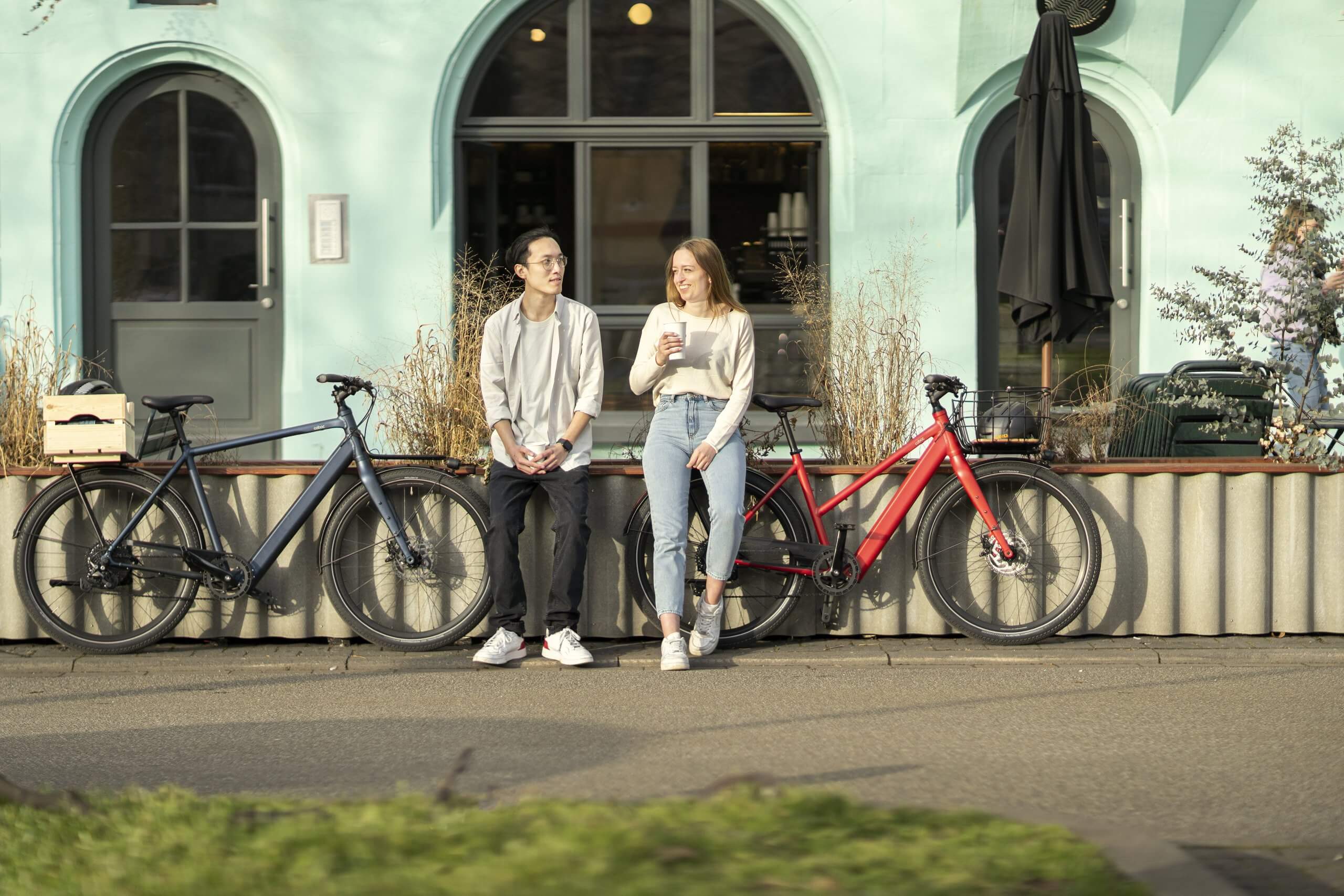 Mann und Frau stehen neben Coboc E-Bikes mit Frontgepäckträger Bristol TPZ und Bristol DMT